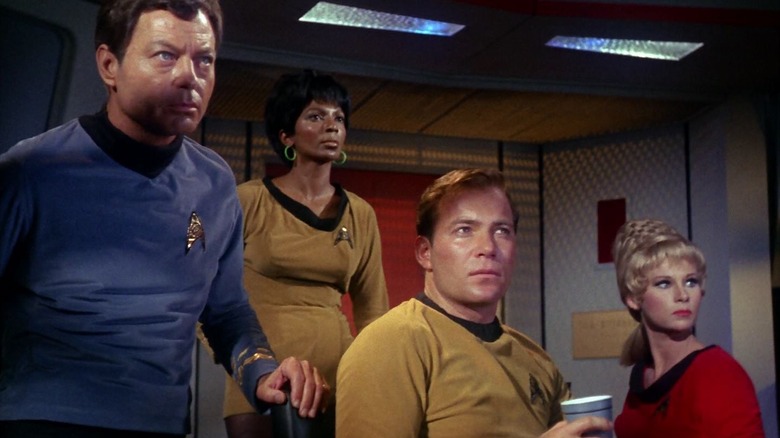 Dr. McCoy, Lieutenant Uhura, Captain Kirk, and Yeoman Rand on the bride of the Enterprise on Star Trek