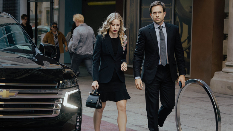 Elle Chapman's Paige McIntosh walks along a New York City sidewalk next to Patrick J. Adams' Russell McIntosh in The Madison