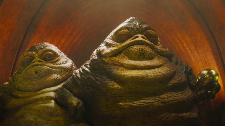 The Hutt twins on their throne holding Mando's helmet in The Mandalorian and Grogu