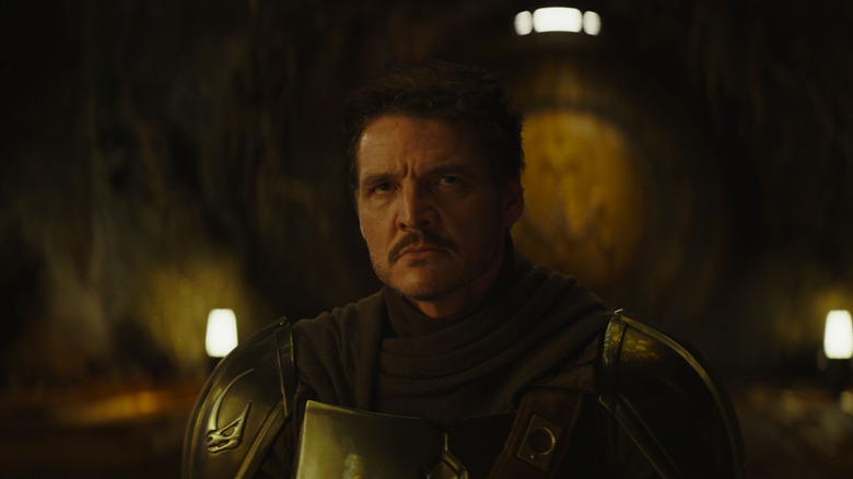 Pedro Pascal as Din Djarin with his helmet off on his knees in The Mandalorian and Grogu