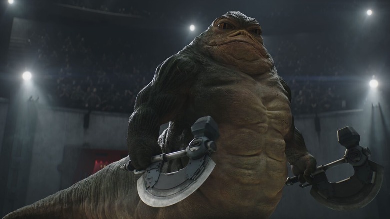 Rotta the Hutt holding twin axes in a fighting arena in The Mandalorian and Grogu