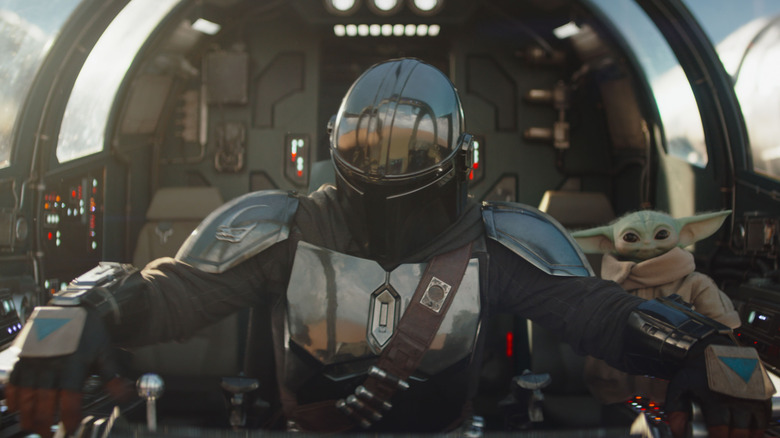 Mando in de cockpit van zijn schip met Grogu in de Mandalorian en Grogu