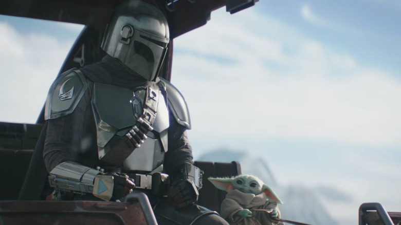 Pedro Pascal's Din Djarin and Grogu riding a wagon in The Mandalorian and Grogu
