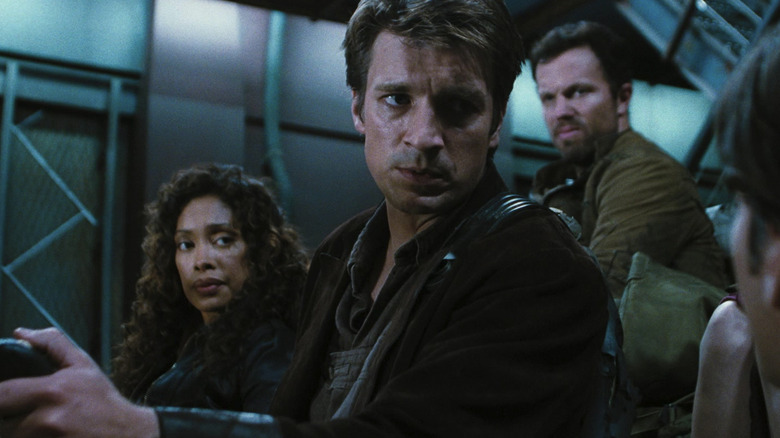 Mal Reynolds, Zoe Washburne, and Jayne Cobb on a transport ship looking at someone off-camera in Serenity
