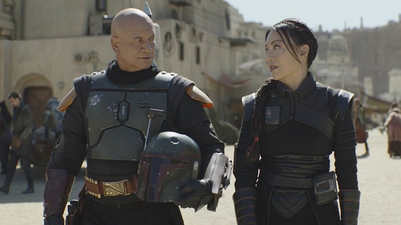Temuera Morrison as Boba Fett and Ming-Na Wen as Fennec Shand walking down the streets of Tatooine in The Book of Boba Fett