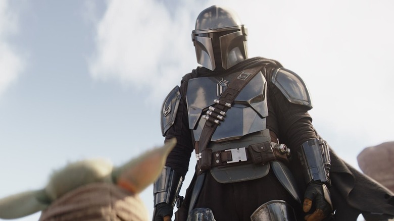 Mando looking down at Grogu in The Mandalorian Season 3