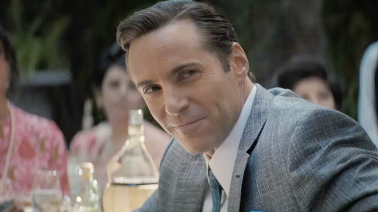 Alessandro Nivola as Dickie Moltisanti smiling in a suit outside in The Many Saints of Newark