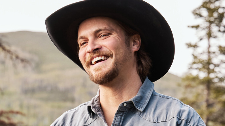 Luke Grimes' Kayce Dutton smiles against a mountainous backdrop in Marshals