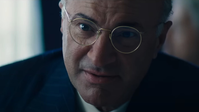 Kevin O'Leary as business manager Marty Reisman wearing glasses and an expensive suit in Marty Supreme