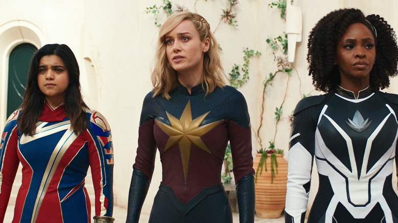 Iman Vellani's Ms. Marvel, Brie Larson's Captain Marvel, and Teyonah Parris's Monica Rambeau stand side by side outside in The Marvels