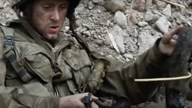 A soldier lights a sticky bomb