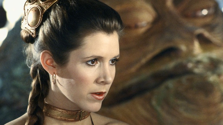 Princess Leia Organa sits in gold bikini beside Jabba the Hutt