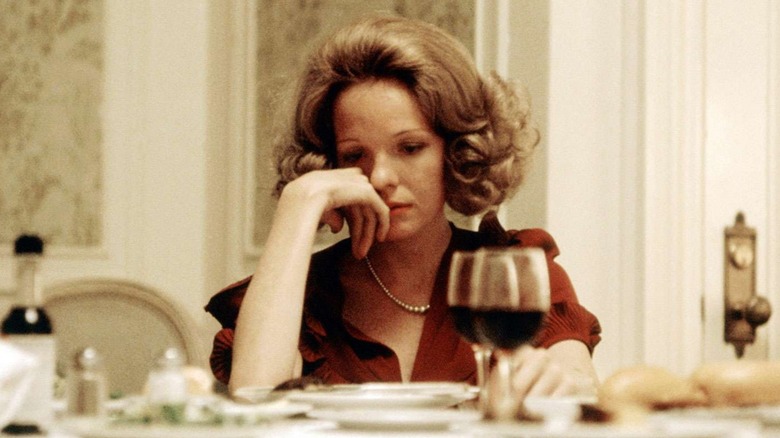 Kay with her hand on her face and glasses of wine in front of her in The Godfather