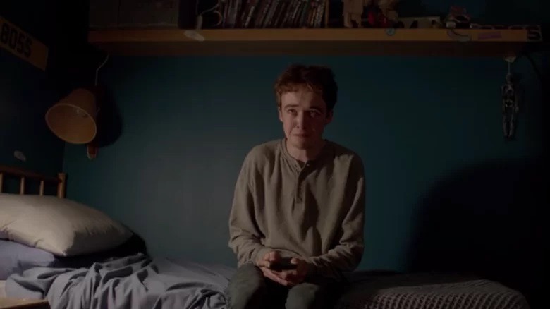 Kenny sits on his bed, crying.