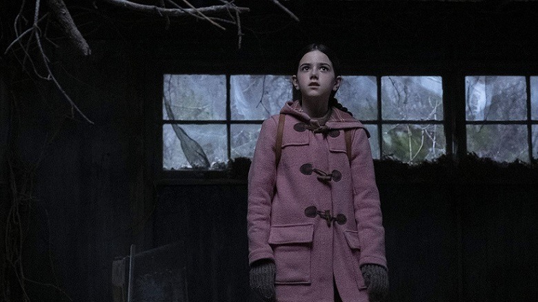 A young girl stands in a deserted house