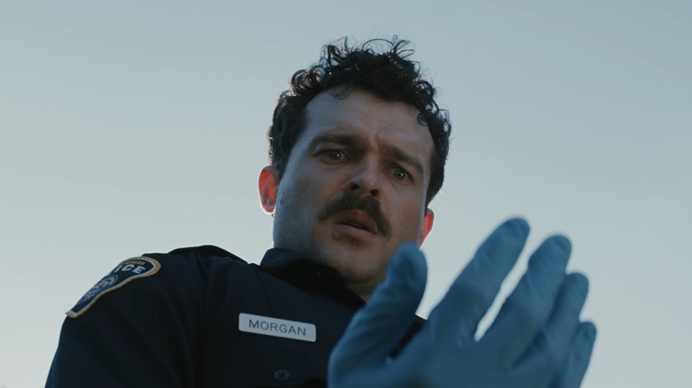 Alden Ehrenreich as Paul looking with fear at his hand in Weapons