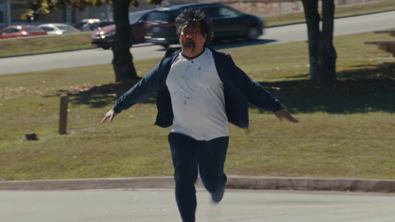 Benedict Wong como Andrew correndo em direção a Justine com um rosto sangrento em armas