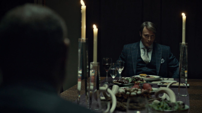 Hannibal sits across from Jack at the dinner table