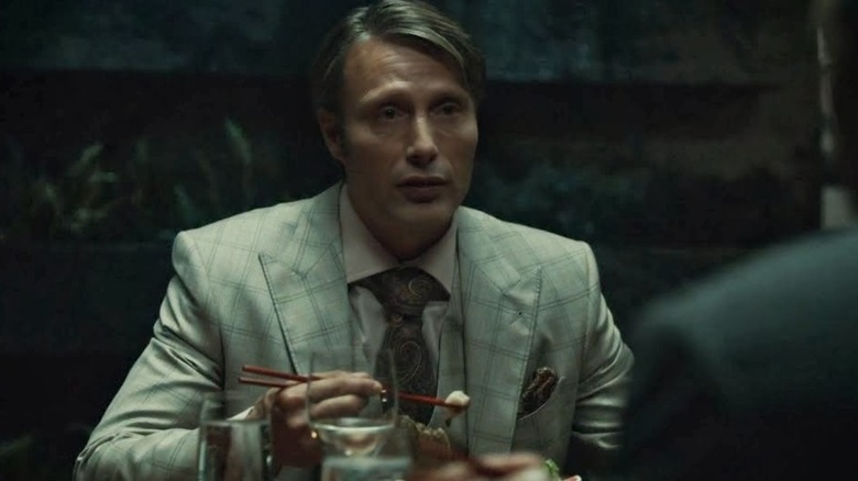 Hannibal picks up a piece of fish with chopsticks