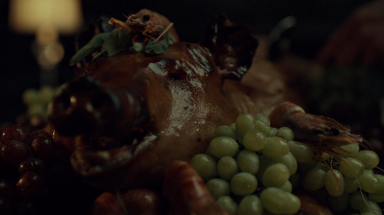 A roast pig on top of a platter of grapes