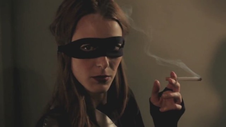 A masked woman smoking a cigarette in 50 Kisses