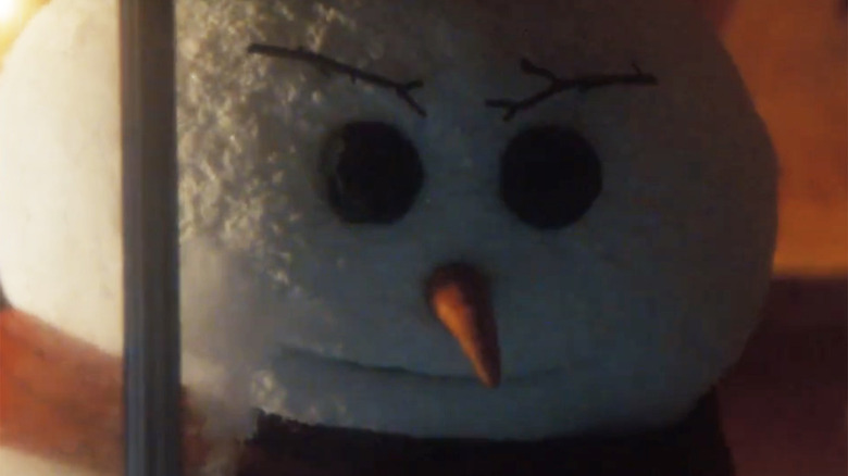 The jealous snowman frowns in anger looking through a window in The Naked Gun (2025)