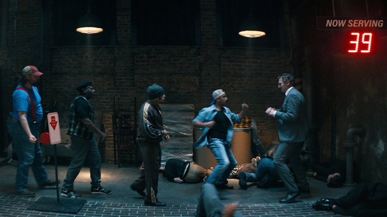 Frank Drebin Jr. (Liam Neeson) fights a line of henchman who are taking numbers to be served in The Naked Gun (2025)