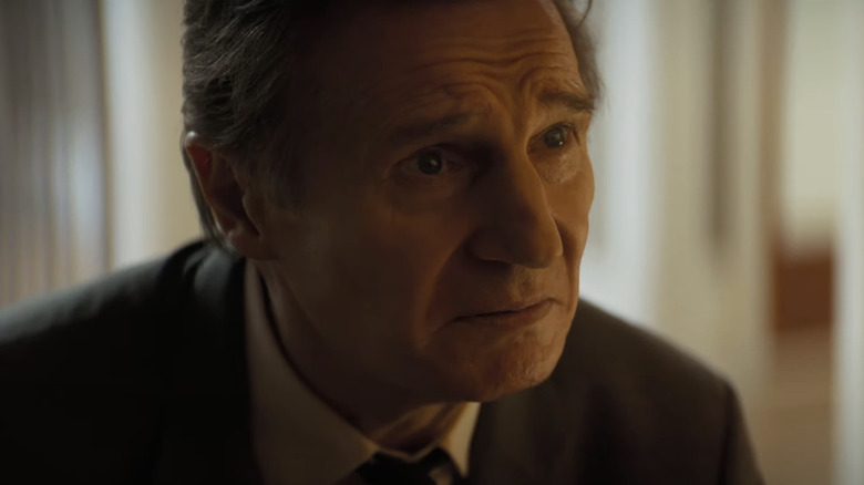 Liam Neeson as Frank Drebin Jr. kneeling in The Naked Gun (2025)