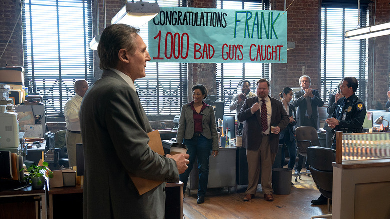 Frank Drebin Jr. (Liam Neeson) is celebrated at Police Squad headquarters for catching 1,000 bad guys in The Naked Gun (2025)
