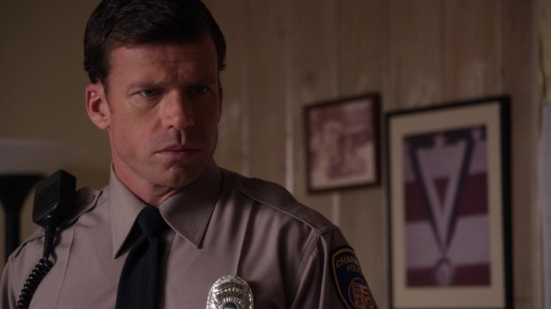 The deputy of Taylor Sheridan, in uniform, seriously looks at something in the sons of anarchy