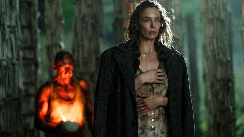 Ralph Fiennes as Dr. Kelson and Jodie Comer as Isla, standing in the Bone Temple at night, in 28 Years Later
