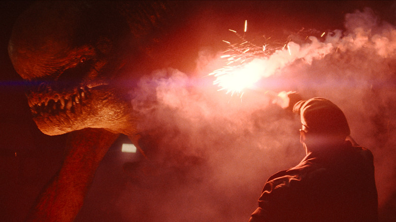 Mahershala Ali as Duncan Kincaid lights a flare to distract a D-Rex in Jurassic World Rebirth
