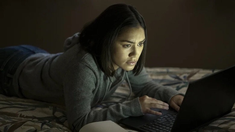 Luciane Buchanan peers into her laptop on a bed as Rose Larkin in The Night Agent