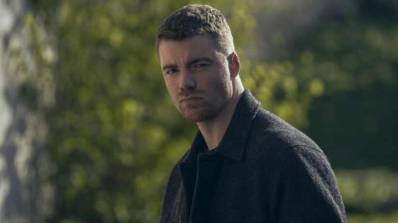 Gabriel Basso as Peter Sutherland standing in front of trees in The Night Agent