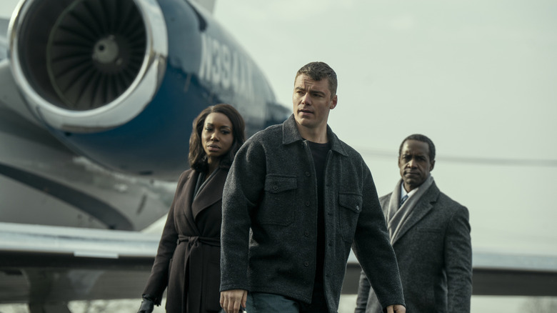 Amanda Warren as Catherine Weaver, Gabriel Basso as Peter Sutherland, and Albert Jones as Aiden Mosley standing by a plane in The Night Agent