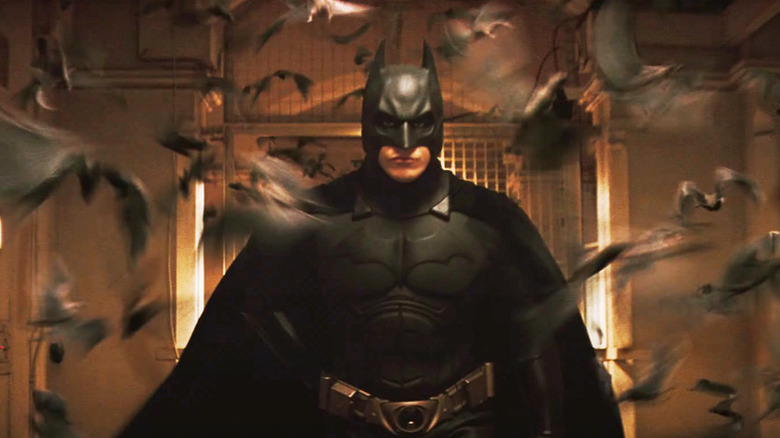 Batman correndo cercado por um golpe de morcegos em Batman Begins