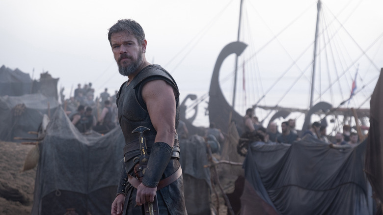 Odysseus stands in front of some boats in The Odyssey