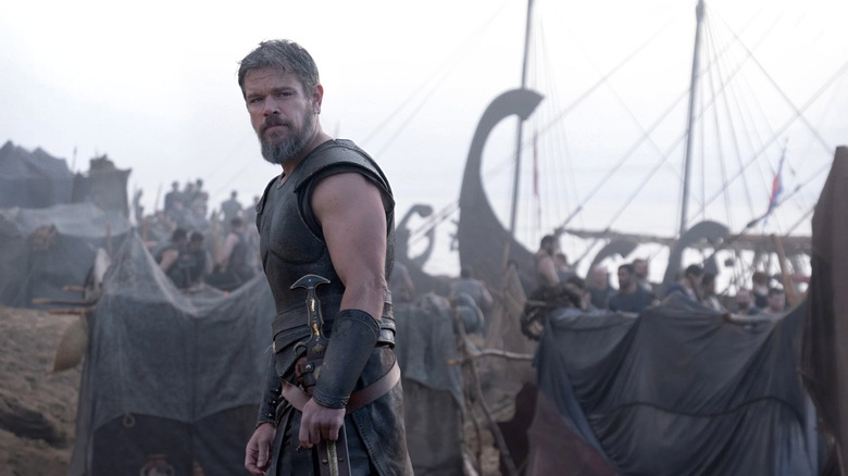 Odysseus standing on a beach next to a ship in The Odyssey