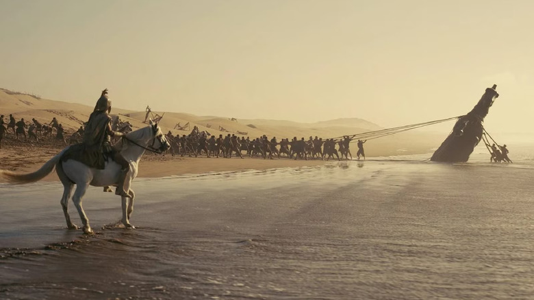 Men pulling the Trojan horse off a beach in The Odyssey (2026)