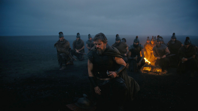 Matt Damon as Odysseus leads several soldiers through a desert at dusk in The Odyssey