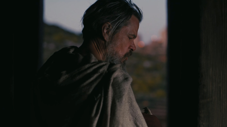 Matt Damon's Odysseus is seen in profile as he stands in a doorway in The Odyssey