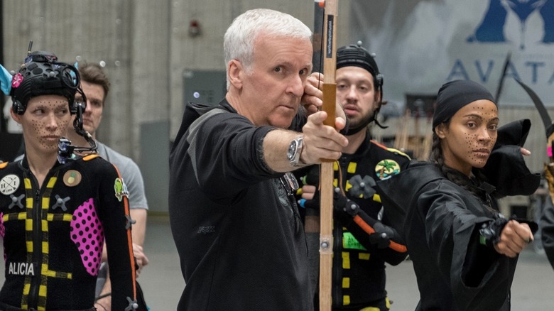 James Cameron holding an archer's bow next to Zoe Saldaña