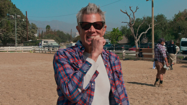 Johnny Knoxville smiling with his hand by his face in the animal pen in Jackass Forever