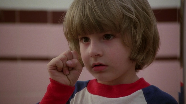 Danny Lloyd's Danny Torrance holds up a fist as he looks in a mirror in The Shining