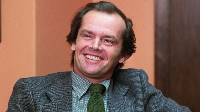 Jack Nicholson's Jack Torrance smiles as he sits in an office in The Shining