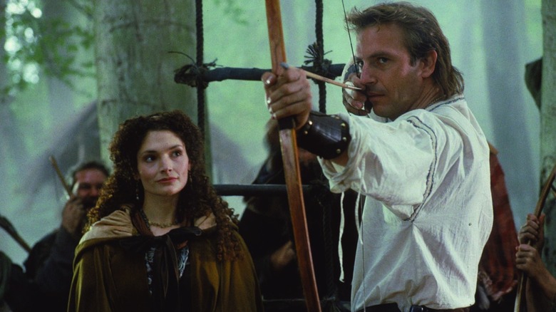 Mary Elizabeth Mastrantonio como Lady Marian observa a Kevin Costner mientras Robin dispara una bala en Robin Hood: Príncipe de los ladrones