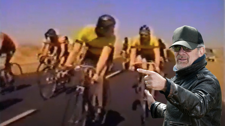 Bicycle riders wearing yellow shirts in a race in Slipstream, with a modern Spielberg pointing at them