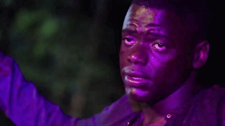 Chris holding his hands in the air in front of a police car in "Get Out"