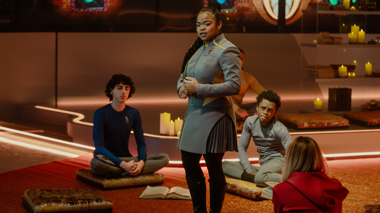 Sam in the middle of some sitting students on Star Trek: Starfleet Academy