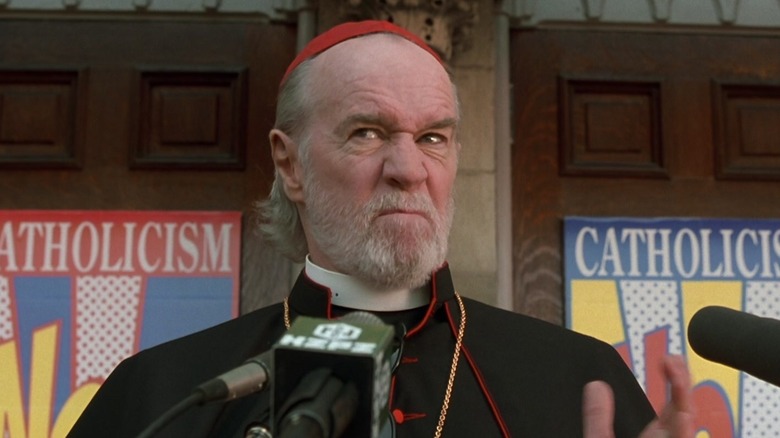 Cardinal Ignatius Glick makes a funny face while speaking at a podium in Dogma